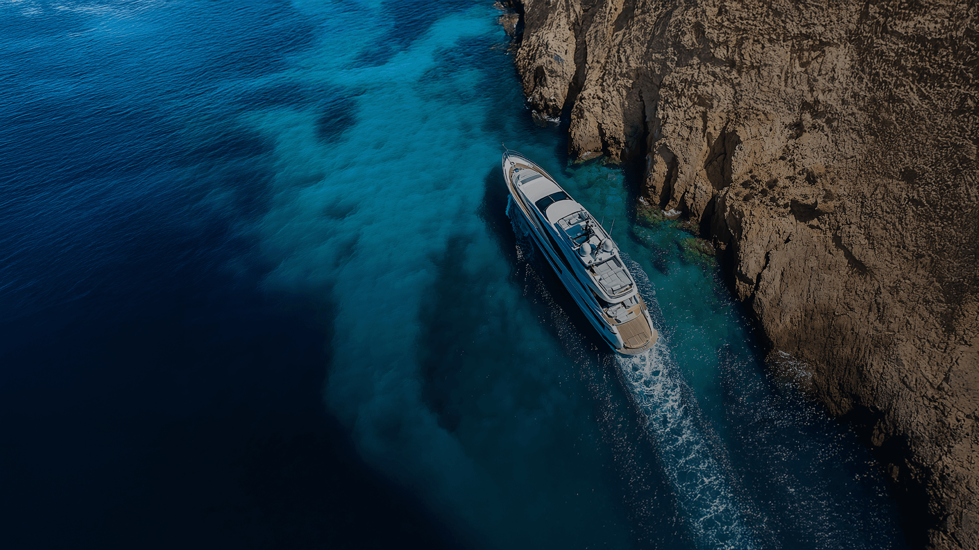 Luxury yacht sailing through turquoise waters near coastal cliffs